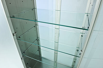 Zoom in einen Katen an dessen Rückseite zwei geschlossene Glastüren sind. Im Schrank sind drei Fachböden aus Glas zu sehen.